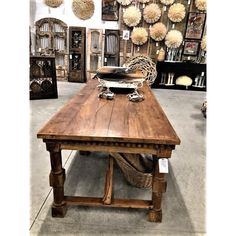 an old wooden table in a store with lots of decorations on the wall behind it