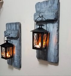 two lanterns are hanging on the wall next to each other with candles burning in them