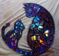 a stained glass cat sitting on top of a white bed next to a wall mounted mirror