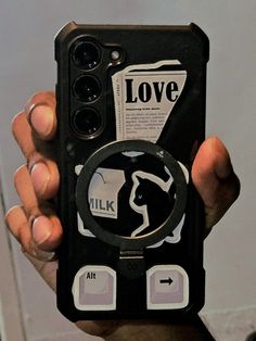 a person holding up a cell phone with stickers on it's back cover