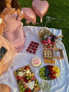 two women sitting at a table with desserts and balloons in the shape of hearts