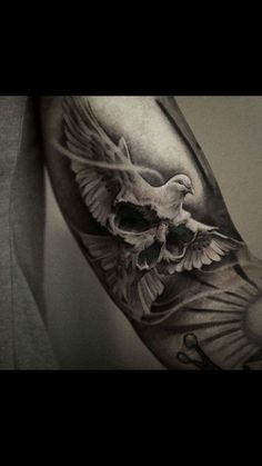 a man's arm with a bird and cross tattoo on the left side of his arm