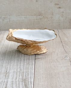 a white and gold bowl sitting on top of a wooden table