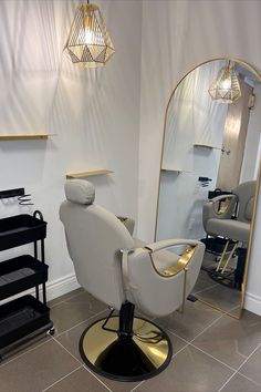 a salon chair sitting in front of a mirror with lights hanging from it's sides