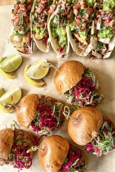 several tacos are lined up on a table with limes and other food items