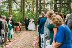 a bride and groom walking down the aisle at their outdoor wedding ceremony in the woods