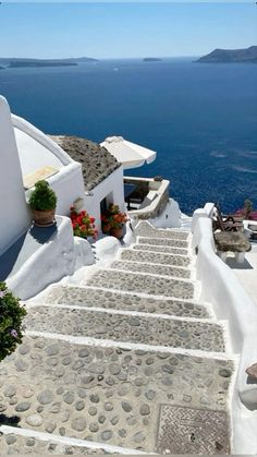 stairs leading up to the top of a white building with blue water in the background