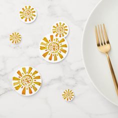 four yellow and white coasters sitting on top of a marble table next to a gold fork