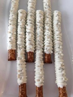 several white and brown candy sticks in a plastic container with silver beads on them, sitting side by side