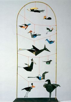 a group of birds that are hanging from a metal rod on a white wall,