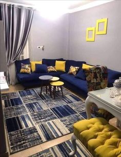 a living room with blue couches and yellow pillows on the rug in front of it