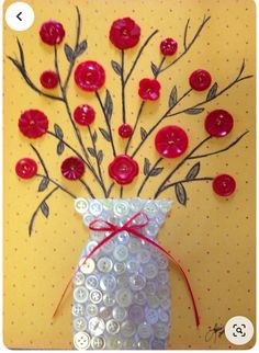 a vase filled with buttons and flowers on top of a yellow wall next to a red ribbon