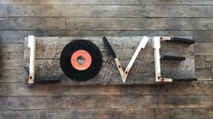 a wooden sign that says love with an old record on it