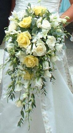 a bride holding a bouquet of yellow and white flowers