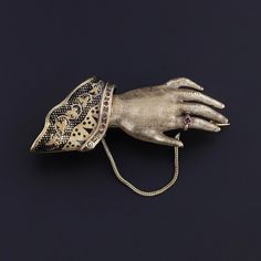 This rare antique, Victorian era brooch (circa 1860) features a hand of 14k gold with a black enamel lace cuff and red glass accents. The piece measures 1.5 inches by 2.2 inches wide, and it is in great condition.  The piece is hollow and weighs 7.28 grams.  We have many other fantastic offerings of period fine jewelry posted on our Etsy store, so please consider browsing our other items. We send all items in individually packaged gift boxes and offer layaway plans! + Trademark Antiques Shop Hom Hands Jewelry, Hourglass Pendant, Hand Brooch, Victorian Hand, Brass Pin, Lace Cuffs, Jewelry Post, Silver Coat, Handmade Wire Jewelry