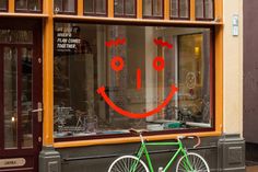 a bicycle parked in front of a store window with a smiley face drawn on it