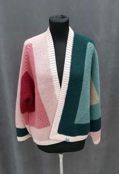 a pink, green and white cardigan sweater on a mannequin head stand