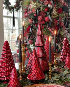 red glass christmas trees and candles on a table