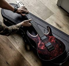 a person holding an electric guitar on top of a hard case