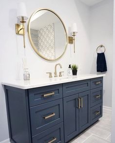 a bathroom with two sinks and a large round mirror on the wall above it's counter