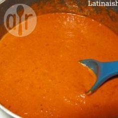 a blue spatula in a pot filled with tomato sauce