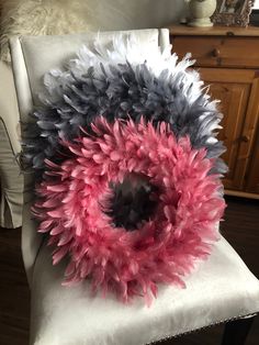 a pink and grey wreath sitting on top of a white chair in a living room