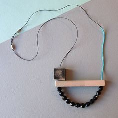 a necklace with black beads and a wooden bar hanging from it's back end