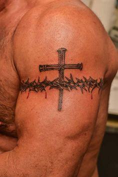 a man with a cross and barbed wire tattoo on his back shoulder is looking at the camera