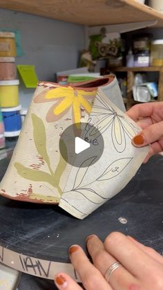 a woman is working on a vase in her studio, with one hand holding it