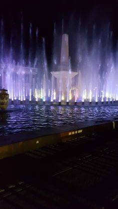 the water fountain is lit up at night