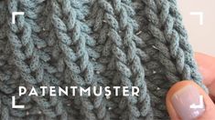 a hand holding a gray knitted object with the words pattenmuster below it