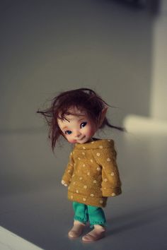 a doll is standing on the floor with her hair flying in the air and looking up