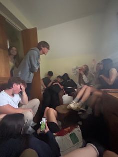 a group of people sitting in a room with one person on the phone and another standing up