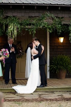 the bride and groom are kissing in front of their wedding party at the ceremony venue