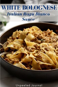 a close up of a plate of food with pasta and meat in it on a table