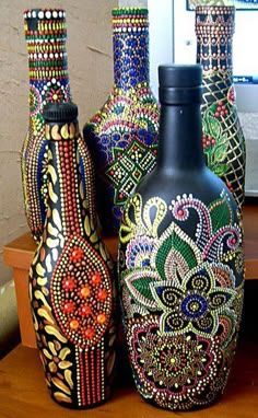 three colorful vases sitting on top of a wooden table next to a computer monitor