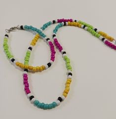 This is a choker necklace with a matching bracelet.  Both pieces are made with seed beads and have silver clasps.  The bead colors include bright pink, white, black, turquoise, yellow and lime green.  The necklace is 18inches long, the bracelet is 7 1/2 inches long and both have a clasp. Green Letter Beads For Festival, Adjustable Multicolor Single Strand Beaded Bracelet, Multicolor Single Strand Bead Choker, Green Letter Beads Necklace For Festival, Green Letter Beads Necklace For Festivals, Multicolor Single Strand Choker, Colorful Adjustable Round Beads Choker, Adjustable Multicolor Single Strand Beaded Necklace, Multicolor Letter Beads Choker With Round Beads