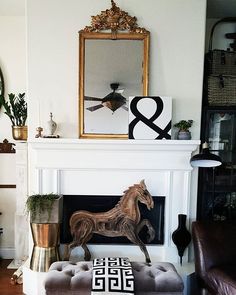 a horse statue sitting on top of a ottoman in front of a fire place with a mirror above it