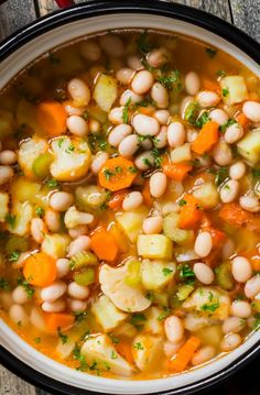 a bowl filled with beans and vegetables on top of a wooden table