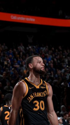 a basketball player standing in front of a crowd with his head turned to the side