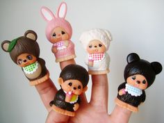 a hand holding five little dolls in different outfits