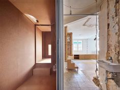 an empty room with exposed brick walls and stone flooring is seen through the open door