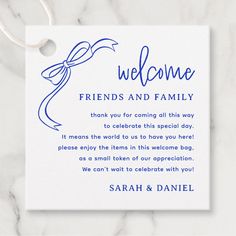 a welcome card for friends and family with a blue ribbon on the front, sitting on a marble surface