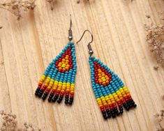 a pair of colorful beaded earrings sitting on top of a wooden table