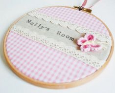 a pink and white checkered table cloth hanging from a wooden frame with a flower on it