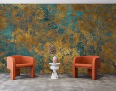 two orange chairs sitting next to each other in front of a green and gold wall