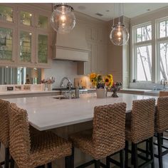 a large kitchen island with four chairs around it and lights hanging from the ceiling above