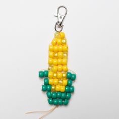 a corn on the cob keychain with green and yellow beads hanging from it