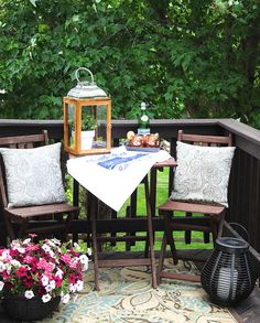 a table and chairs on a deck with flowers