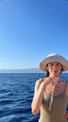 a woman wearing a straw hat standing on the back of a boat